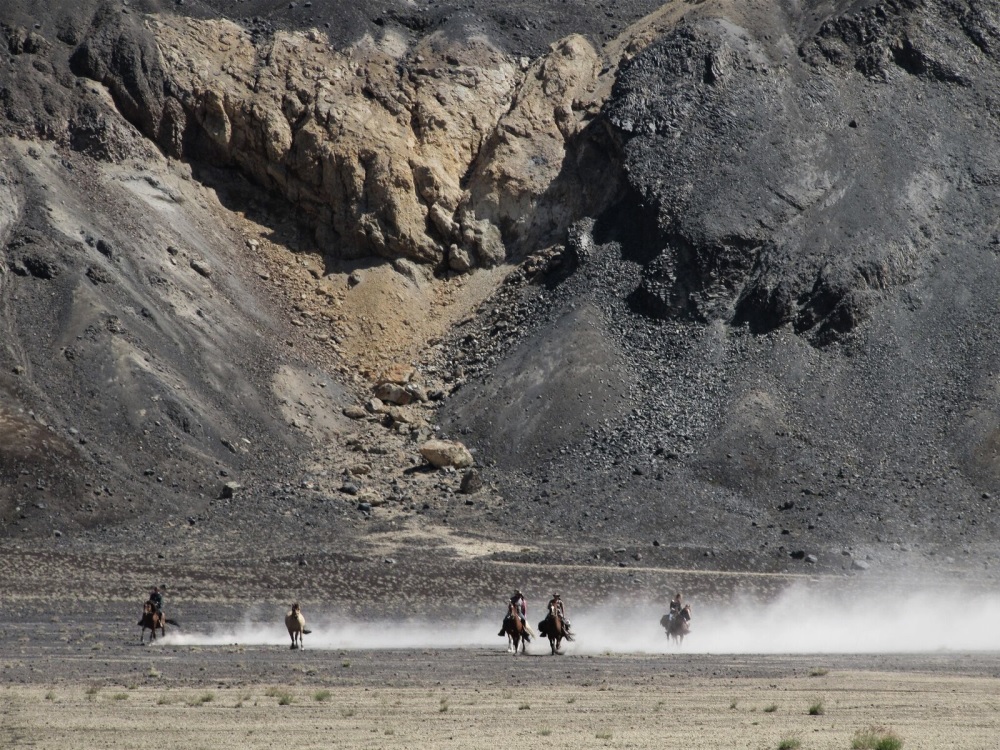 Riders galopping in front of a mountain on the Crossing the Andes ride through Chile and Argentina